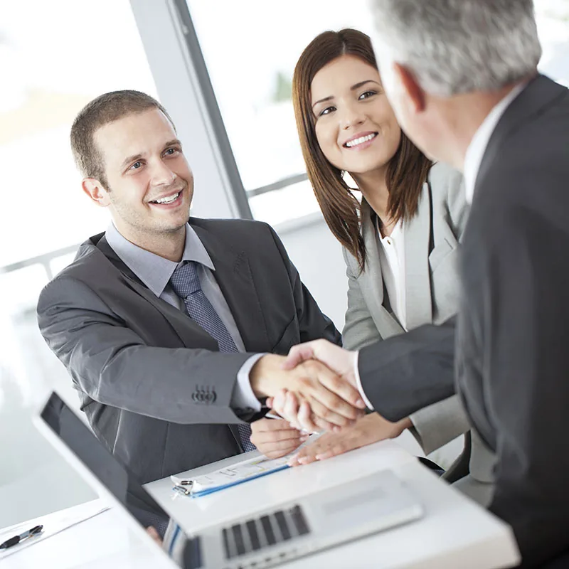 A loan officer shaking hands with clients across a desk
